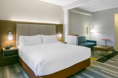 a bedroom with a large white bed and a blue chair at Holiday Inn Express Mount Arlington by IHG in Mount Arlington