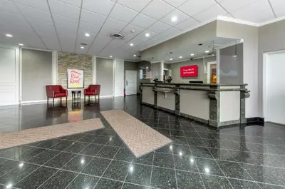 a lobby with a waiting room with red chairs at Red Roof PLUS Woodbridge - Carteret in Carteret