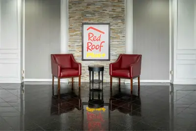two red chairs and a cocacola sign in a room at Red Roof PLUS Woodbridge - Carteret in Carteret