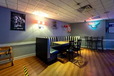 a restaurant with a bar with chairs and a table at Red Roof PLUS Woodbridge - Carteret in Carteret