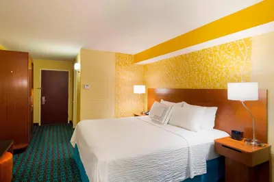 a hotel room with a large bed with white sheets at Fairfield Inn & Suites by Marriott Paramus in Paramus