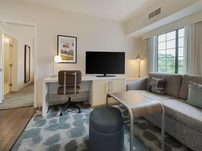 a living room with a couch and a desk with a tv at Homewood Suites by Hilton Parsippany-Troy Hills in Parsippany