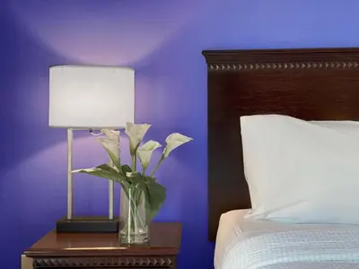 a vase of flowers on a table next to a bed at Holiday Inn South Plainfield-Piscataway by IHG in South Plainfield
