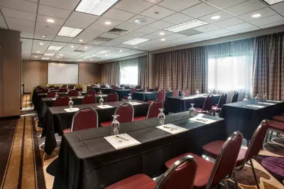 a conference room with tables and chairs and a screen at Holiday Inn Princeton by IHG in Princeton