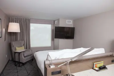 a bedroom with a bed and a chair and a television at Hilton Garden Inn Springfield in Springfield