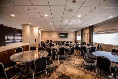 a conference room with tables and chairs and a screen at Hotel Indigo Harrisburg - Hershey by IHG in Harrisburg