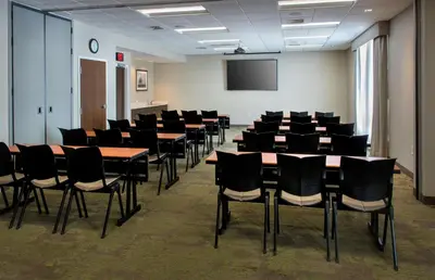 a conference room with tables and chairs and a screen at Hampton Inn Middletown in Middletown