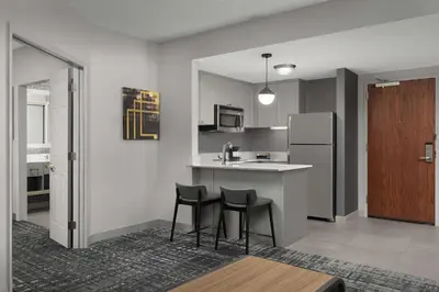 a kitchen with two bar stools and a refrigerator at Homewood Suites by Hilton Reading-Wyomissing in Wyomissing