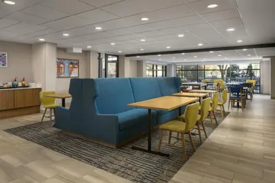 a waiting room with a blue couch and tables and chairs at Hampton Inn - York in York