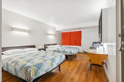 a hotel room with two beds and a table at Motel 6-Piscataway, NJ in Piscataway