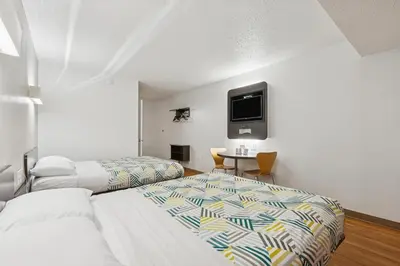 a hotel room with two beds and a tv on the wall at Motel 6-Piscataway, NJ in Piscataway