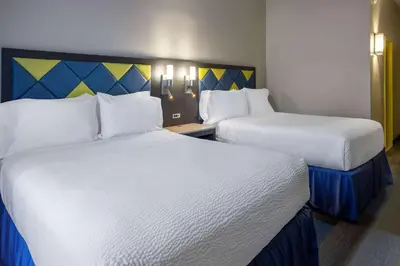 two beds in a hotel room with white sheets at Days Hotel by Wyndham North Bergen in North Bergen