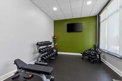 a gym with a green wall and a row of tread machines at Spark By Hilton Bensalem Philadelphia in Bensalem