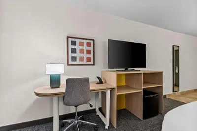 a room with a desk with a television and a chair at Spark By Hilton Bensalem Philadelphia in Bensalem