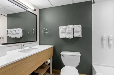 a bathroom with a toilet and a sink and a mirror at Spark By Hilton Bensalem Philadelphia in Bensalem
