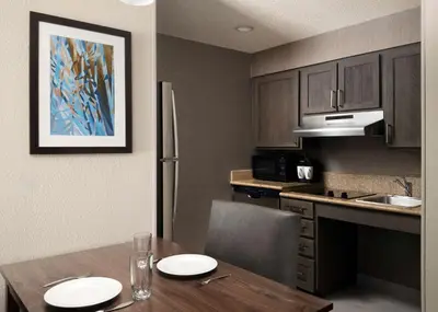 a kitchen with a wooden table and a kitchen with a refrigerator at Homewood Suites by Hilton Somerset in Somerset