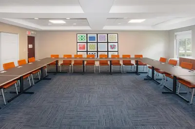 a conference room with long tables and orange chairs at Holiday Inn Express Haskell-Wayne Area by IHG in Haskell