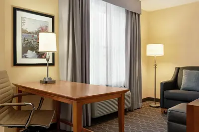 a hotel room with a desk and a chair and a couch at Homewood Suites by Hilton Allentown-Bethlehem Airport in Bethlehem