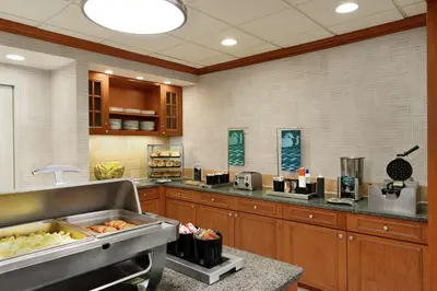a kitchen with wooden cabinets and a counter with food at Homewood Suites by Hilton Allentown-Bethlehem Airport in Bethlehem