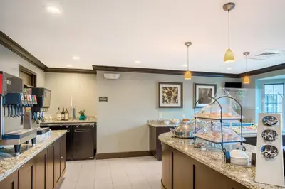 a large kitchen with a counter with many dishes at Staybridge Suites Wilmington-Newark by IHG in Newark