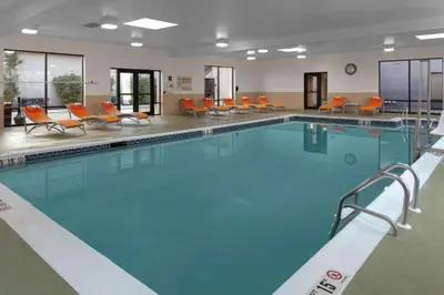 a large swimming pool with orange chairs in a building at Hampton Inn Woodbridge in Woodbridge