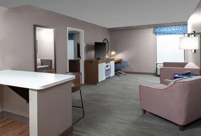 a living room with chairs and a couch and a tv at Hampton Inn Woodbridge in Woodbridge