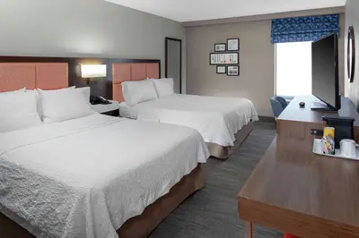 a hotel room with two beds and a television at Hampton Inn Woodbridge in Woodbridge