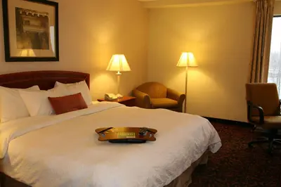 a hotel room with a bed with a suitcase on it at Hampton Inn Woodbridge in Woodbridge