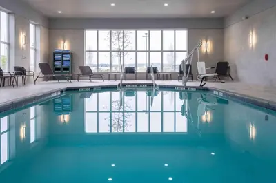 a swimming pool in a hotel with chairs and tables at Homewood Suites by Hilton Philadelphia Plymouth Meeting in Plymouth Meeting
