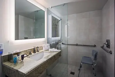 a bathroom with a sink and a mirror and a chair at Crowne Plaza Hotel Philadelphia - King of Prussia by IHG in King of Prussia