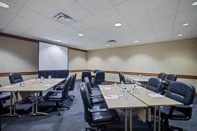 a conference room with tables and chairs and a screen at Crowne Plaza Hotel Philadelphia - King of Prussia by IHG in King of Prussia