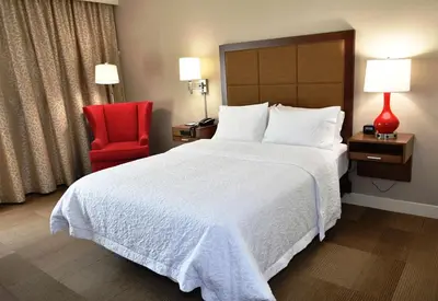 a hotel room with a bed and a red chair at Hampton Inn & Suites Bethlehem in Bethlehem