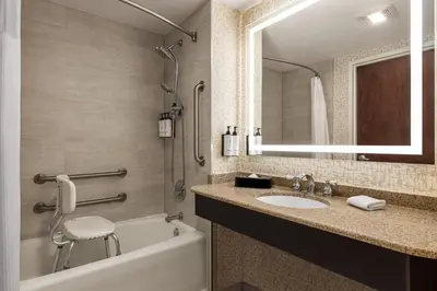 a bathroom with a tub and a sink and a mirror at Crowne Plaza Edison by IHG in Edison
