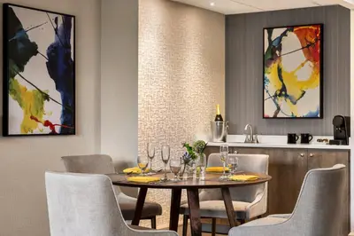 a dining room with a table and chairs and a kitchen at Crowne Plaza Edison by IHG in Edison