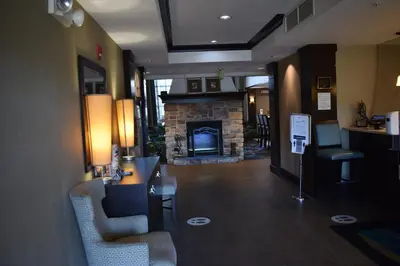 a living room with a fireplace and two chairs at Staybridge Suites Cranbury - South Brunswick by IHG in Cranbury