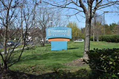 a blue sign in a park next to a tree at Staybridge Suites Cranbury - South Brunswick by IHG in Cranbury