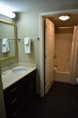a bathroom with a sink and a mirror and a tub at Staybridge Suites Cranbury - South Brunswick by IHG in Cranbury