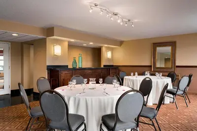 a conference room with tables and chairs and a mirror at Crowne Plaza Englewood by IHG in Englewood