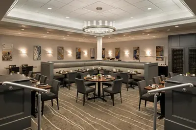 a restaurant with tables and chairs and a chandelier at Crowne Plaza Englewood by IHG in Englewood