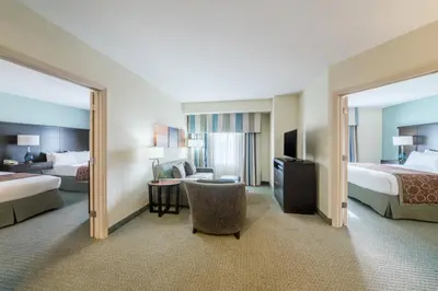 a hotel room with two beds and a chair at Staybridge Suites Wilmington - Brandywine Valley by IHG in Glen Mills