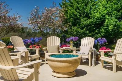 a group of chairs and a large planter in a yard at Staybridge Suites Wilmington - Brandywine Valley by IHG in Glen Mills