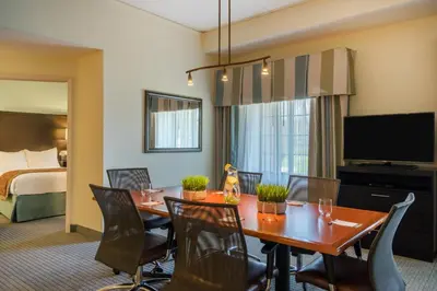 a hotel room with a table and chairs and a bed at Staybridge Suites Wilmington - Brandywine Valley by IHG in Glen Mills