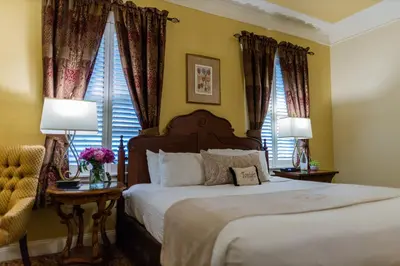 a bedroom with a bed with two lamps and two windows at The Inn at Leola Village, a Historic Hotel of America in Lancaster