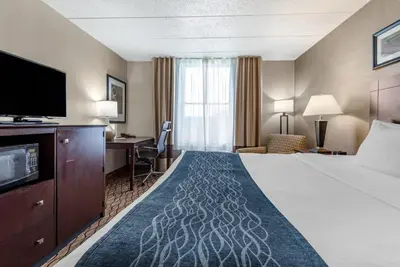 a hotel room with a bed and a flat screen tv at Comfort Inn & Suites Glen Mills - West Chester in Glen Mills