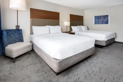 two beds and a chair in a hotel room at Holiday Inn Express & Suites Ft. Washington - Philadelphia by IHG in Fort Washington
