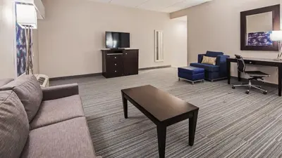 a living room with a couch and a table and a desk at Best Western Plus Wilkes Barre-Scranton Airport Hotel in Pittston