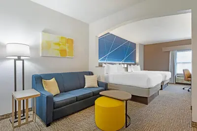 a hotel room with a bed and a blue couch at Comfort Suites East Brunswick - South River in East Brunswick