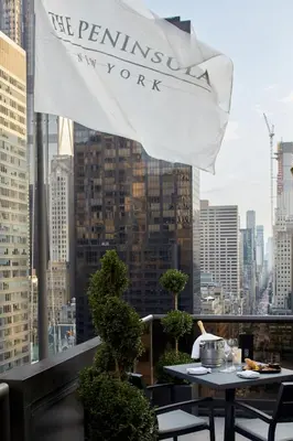 a flag on the roof of a building with a table at The Peninsula New York in New York