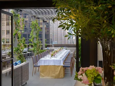 a long table on a balcony with a view of a city at The Peninsula New York in New York