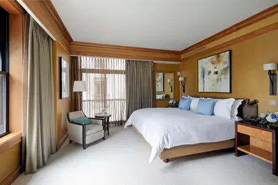 a hotel room with a large bed and a chair at The Peninsula New York in New York